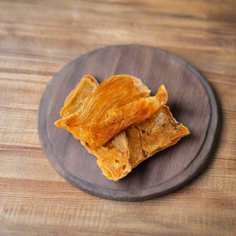 Pieces of Chicken Jerky pet treat on chopping board