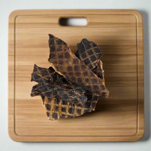 Pieces of Emu Jerky pet treat on chopping board