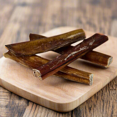 Thick beef pizzle sticks presented on a wooden chopping board